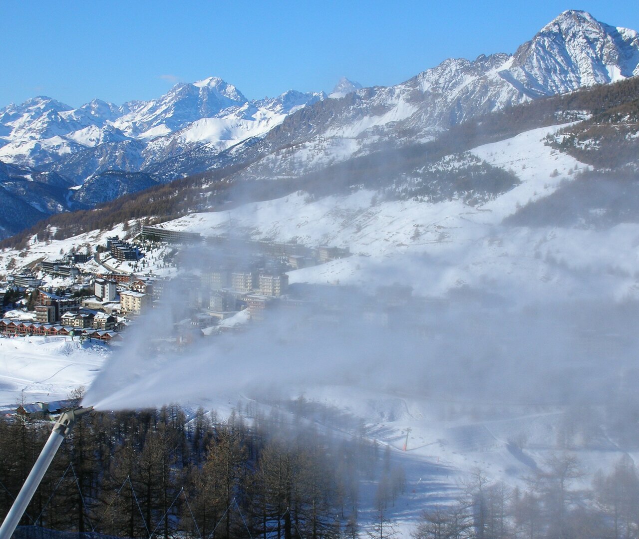 Le Valli Olimpiche sullo sfondo di un cannone spara neve.